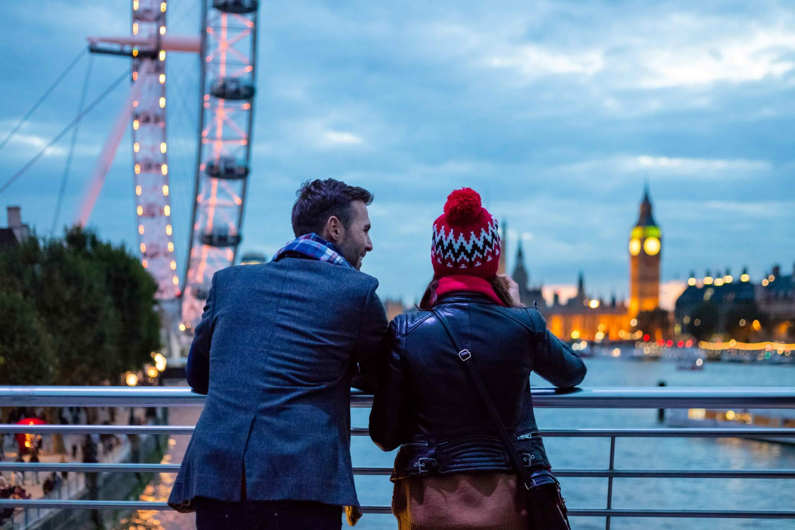 two tourists overlooking river Thames with view of London Eye and Big Ben