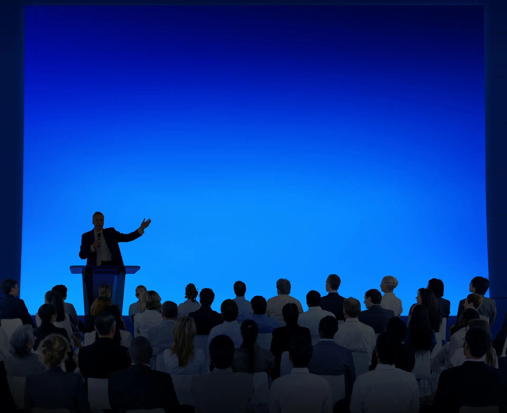 Image of speaker in front of audience on stage