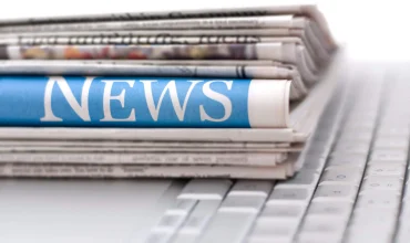 Stack of newspapers resting on laptop keyboard