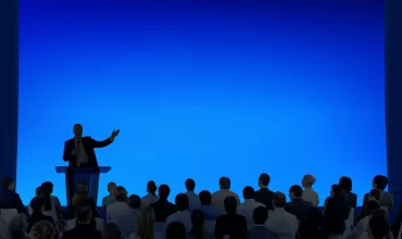 Image of speaker in front of audience on stage